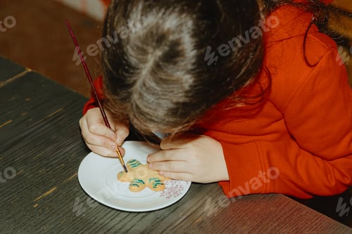 Preview: One girl is coloring cookies while sitting at the table.