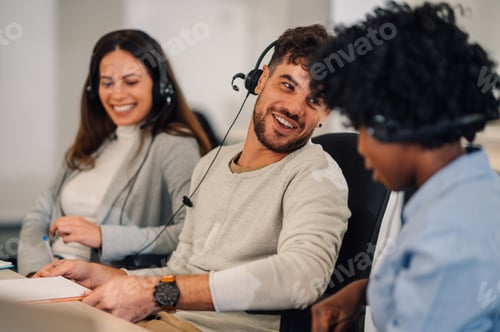 Preview: A call center operator is sitting at office with multiracial colleagues.