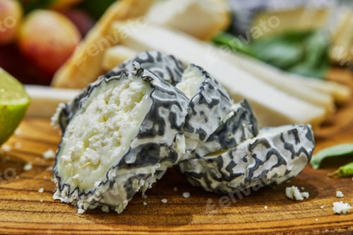 Preview: Slicing of selected cheeses on a wooden board with grapes, lime and pineapple and herbs