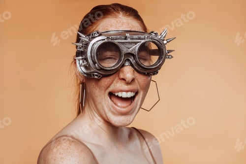 Preview: Cheerful redhead woman with freckles wears steam punk googles