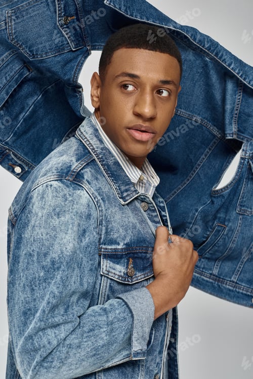 Preview: young trendy african american man in stylish denim outfit posing on white backdrop, fashion