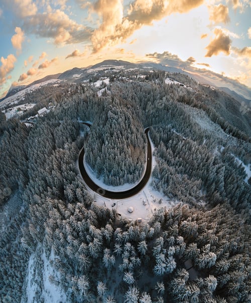 Preview: Aerial view of winter landscape with snow covered mountain hills and winding forest road in morning.