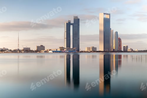 Preview: Abu Dhabi skyline at sunrise with skyscrapers and their reflection in the sea. Establishing shot.