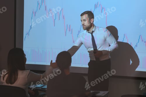 Preview: Man is standing near projector and showing graphs and business graphs.