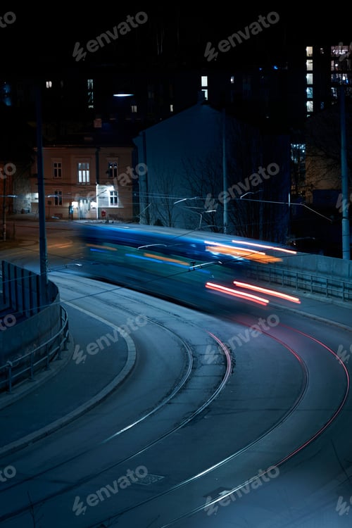 Preview: Vertical long exposure of a tram on a calm street in Oslo at night. Nighttime lights