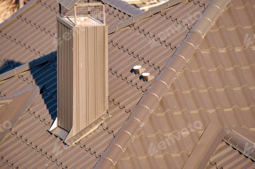 Preview: Chimney on house roof top covered with metallic shingles under construction. Tiled covering of