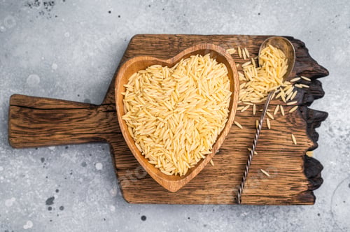 Preview: Raw Orzo pasta, uncooked dry Italian risoni in a bowl. grey background. top view