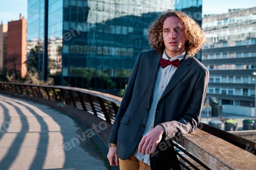 Preview: Man posing while leaning on bridge railing.