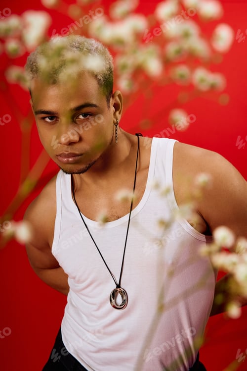 Preview: Young man with dyed hair showcases trendy style in vibrant red studio setting