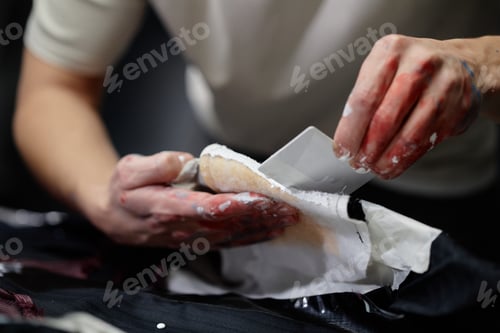 Preview: Hands of Male Fashion Designer Painting Clothes with White Using Card Indoors