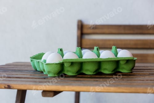 Preview: Chicken eggs in box on a wooden table at home.