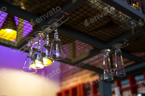 Preview: Empty wine or cocktail glasses hang on the bar in a bar or pub