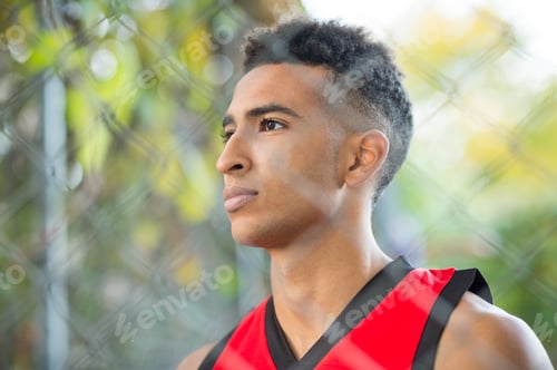 Preview: View through wire fence of young male athlete