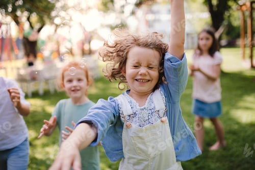 Preview: Small children standing outdoors in garden in summer, playing.