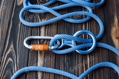 Preview: Isolated photo of climbing equipment. Parts of carabiners lying on the wooden table