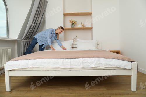 Preview: A young woman makes a bed in an apartment