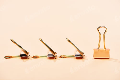 Preview: Row of Paper Clips on Beige Background With Copy Space