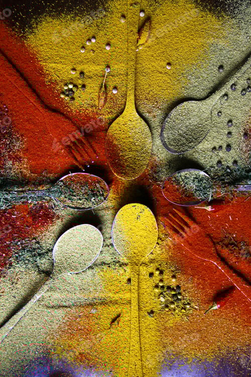 Preview: Top view of metal cutlery arranged in a circle covered with different spices