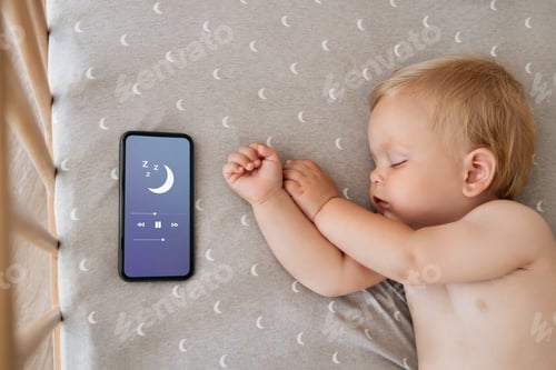 Preview: Upper view of baby napping in his bed next to phone playing lullaby in sleeping app for baby