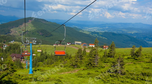 Vorschau: Seilbahn in Bewegung auf dem Berggipfel vor bewölktem blauem Himmel. Sport und aktives Leben
