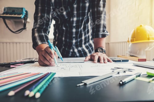 Preview: Male architects or engineers write a draft of the construction project on the blueprint.