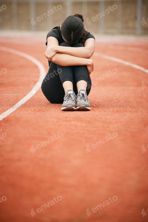 Preview: Today has been tough. Shot of a young woman looking upset while sitting on the track.