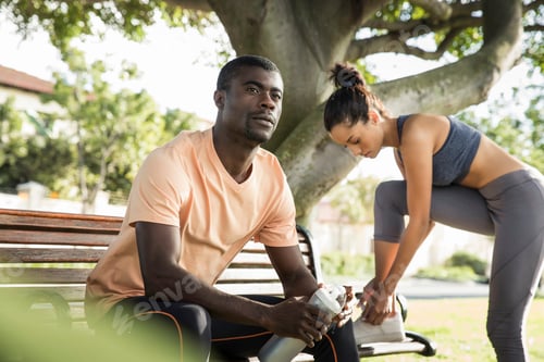 Preview: Man wearing sports clothes sitting on park bench looking away