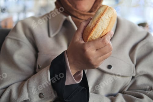 Preview: Woman holding a pastry in a cozy cafe setting during daytime
