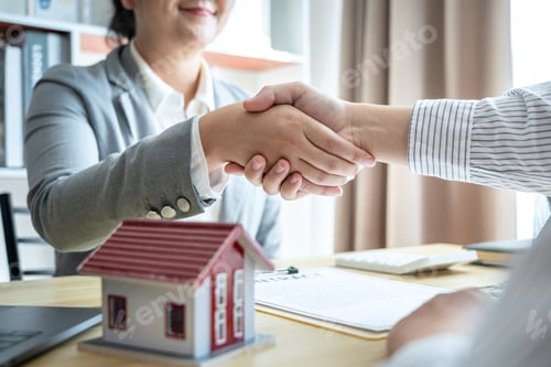 Preview: Estate agent and customers shaking hands together celebrating finished contract after signing