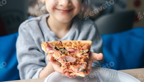 Preview: An appetizing piece of pizza in the hands of a little girl.