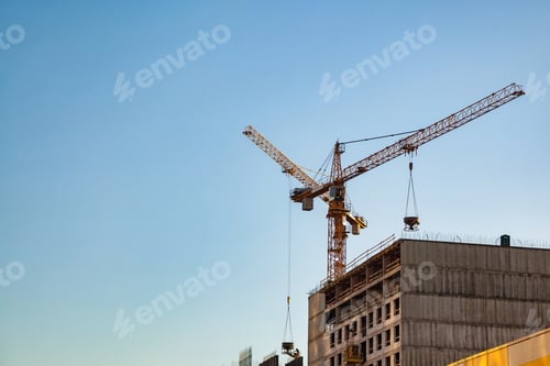 Preview: Urban Construction Site With Cranes Working Against a Clear Blue Sky