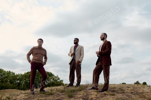 Preview: Stylish men embracing autumn hues while posing in a tranquil field setting