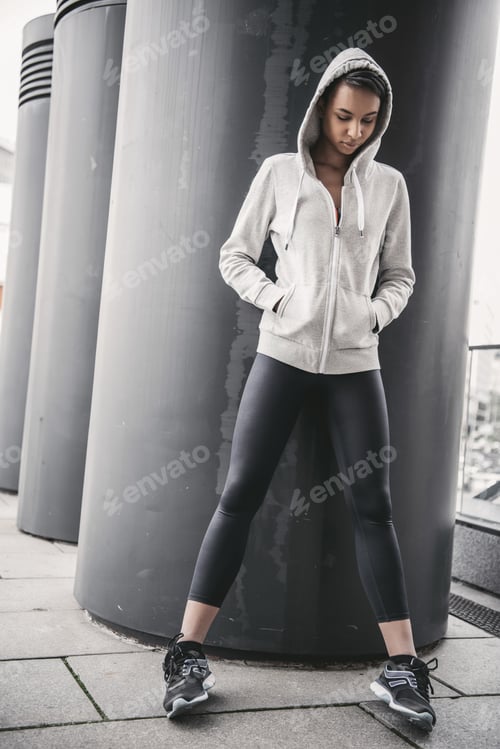 Preview: Attractive young african american sportswoman in hood posing at stadium