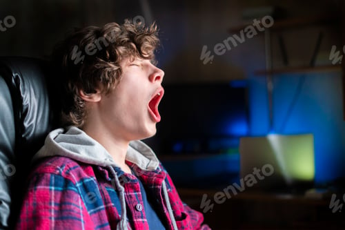 Preview: young man yawn at night time sitting in armchair b