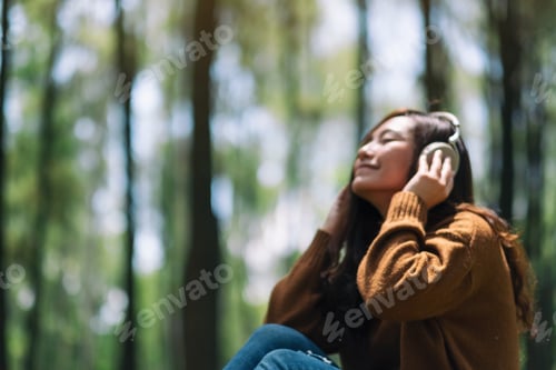 Preview: a beautiful asian woman enjoy listening to music with headphone in the park