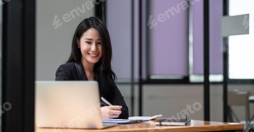Preview: Happy young asian businesswoman sitting on her workplace in the office. Young woman working at