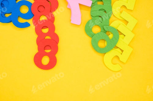 Preview: Flat lay of arranged colorful wooden numbers on a yellow surface - space for text
