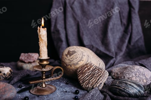 Preview: Burning candle and stones on the witch table.