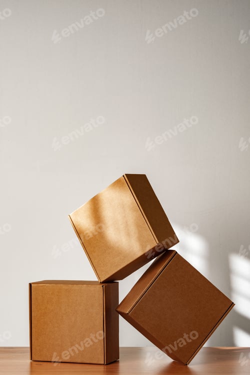 Preview: Three Cardboard Boxes Stacked on a Wooden Surface in a Room With Natural Light
