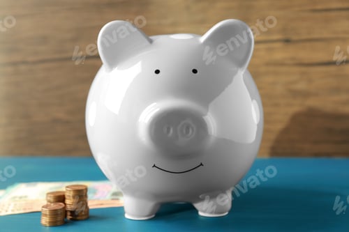 Vista previa: Ceramic piggy bank, banknotes and coins on blue wooden table, closeup