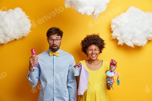 Preview: Beautiful young couple expect baby pose with stuff for newborn prepare to become parents isolated ov