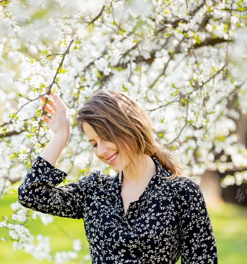 Preview: Young girl in dark dress stay near a flowering tree