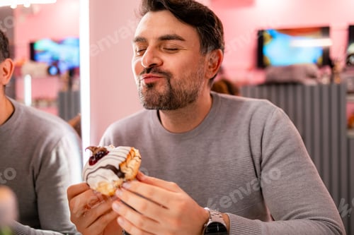 Preview: Man enjoys dessert in a bright caf? while sitting at a table with a friend nearby
