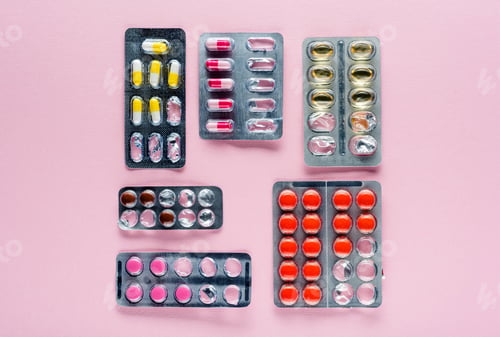 Preview: top view of various medicine in blister packs on pink