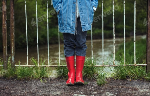 Preview: Woman in a red boots and denim jacket on a brdige under a river in country