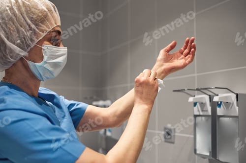 Preview: Close-up of a doctor washing his hands using a disinfectant dispenser.