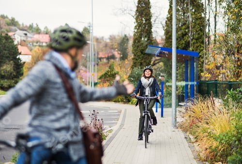 Preview: An active senior couple with electrobikes cycling outdoors on pathway in town.