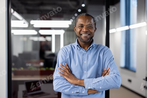 Preview: Confident African American businessman smiling with arms crossed in modern office setting