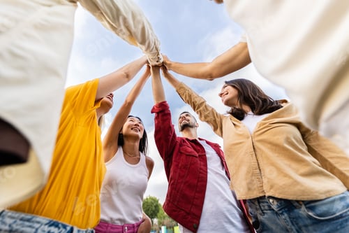 Preview: Young group of happy people stacking hands outside