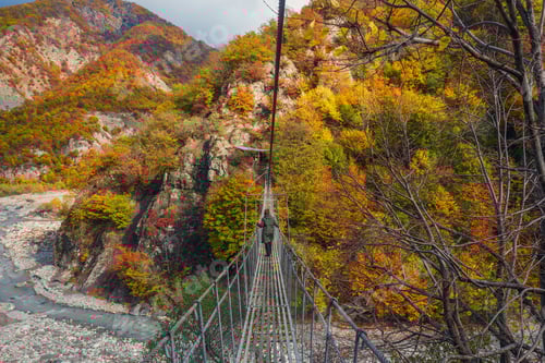 Preview: A girl walks on a suspension bridge in the mountains